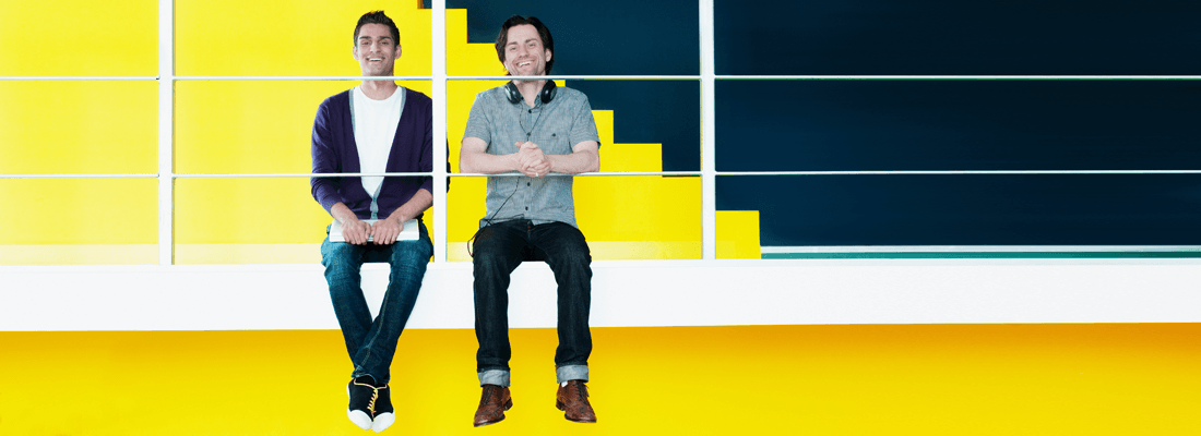 Two happy men against a yellow background in an office